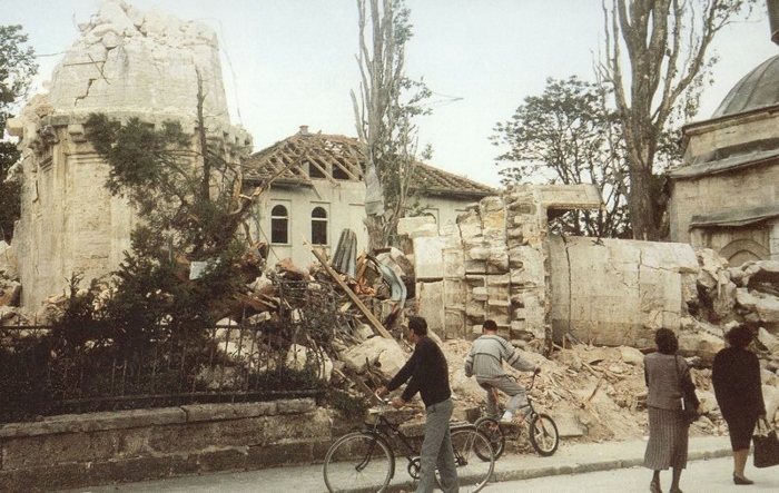 x1.Citizens of Banja Luka stare at the remains of the Ferhadija Mosque on the morning of 8 May 1993. The turbe(mausoleum)of Ferhad-paša, the mosque’s founder, far right, was demolished later in the year on 15 December.©Estate of Aleksander Aco Ravlić